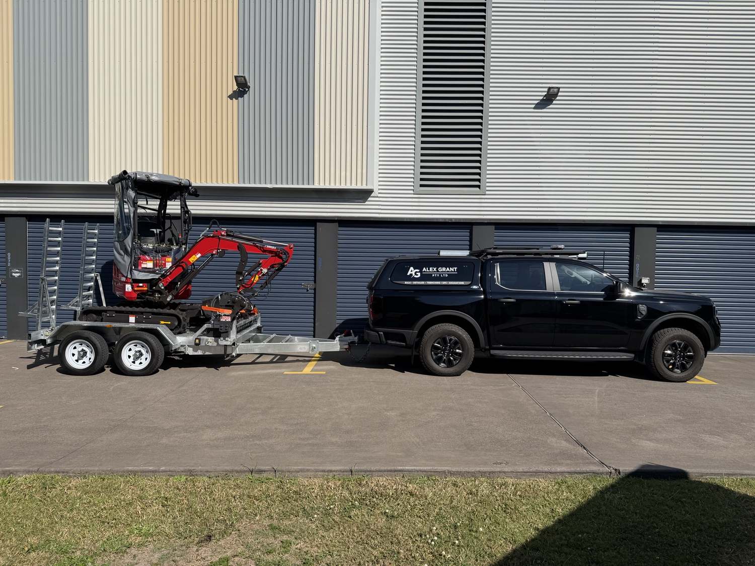 The excavator loaded on its trailer behind the Grant's Digger Hire ute, ready to deliver