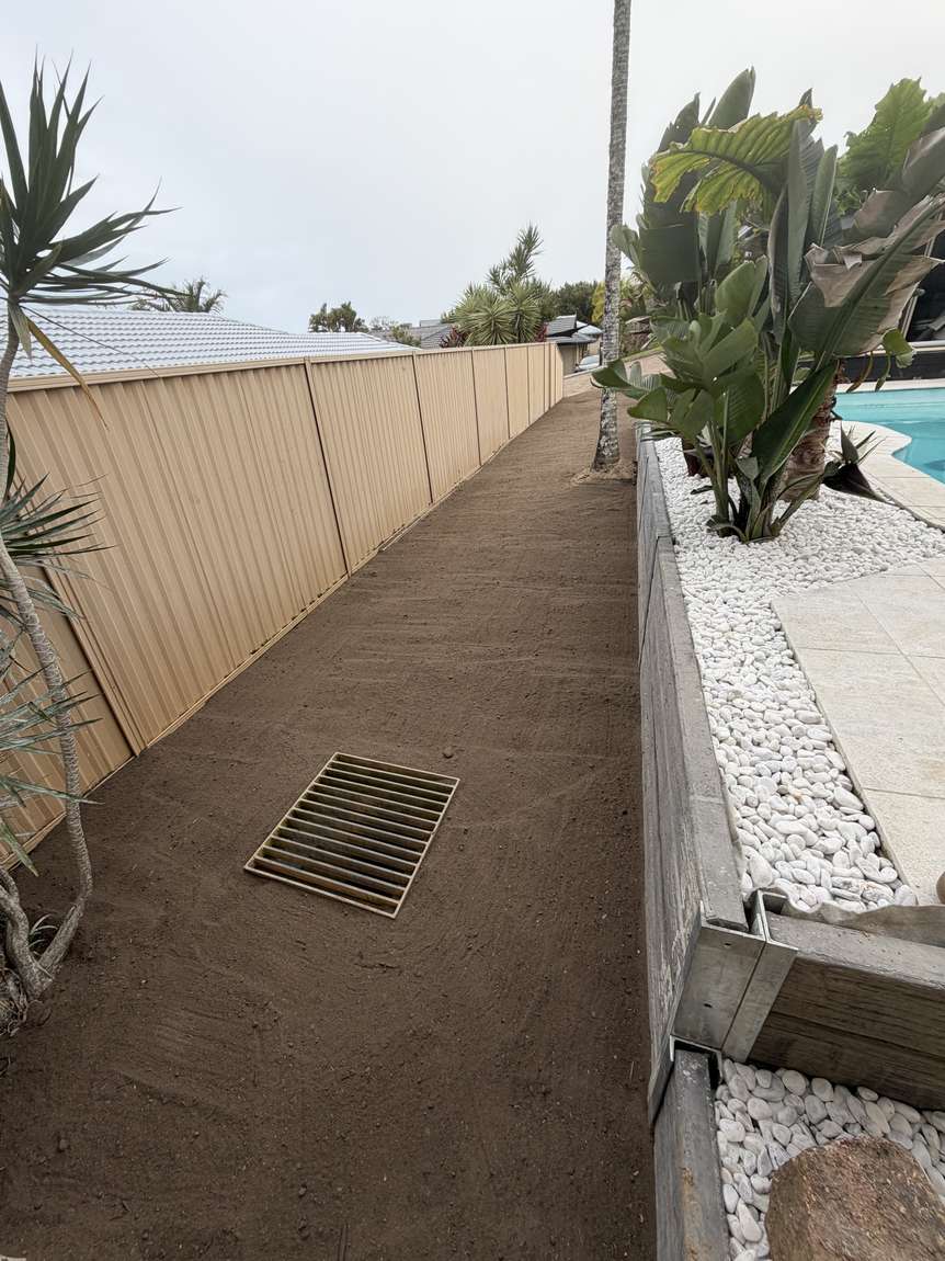 The same side yard after work: level graded ground with a new drain