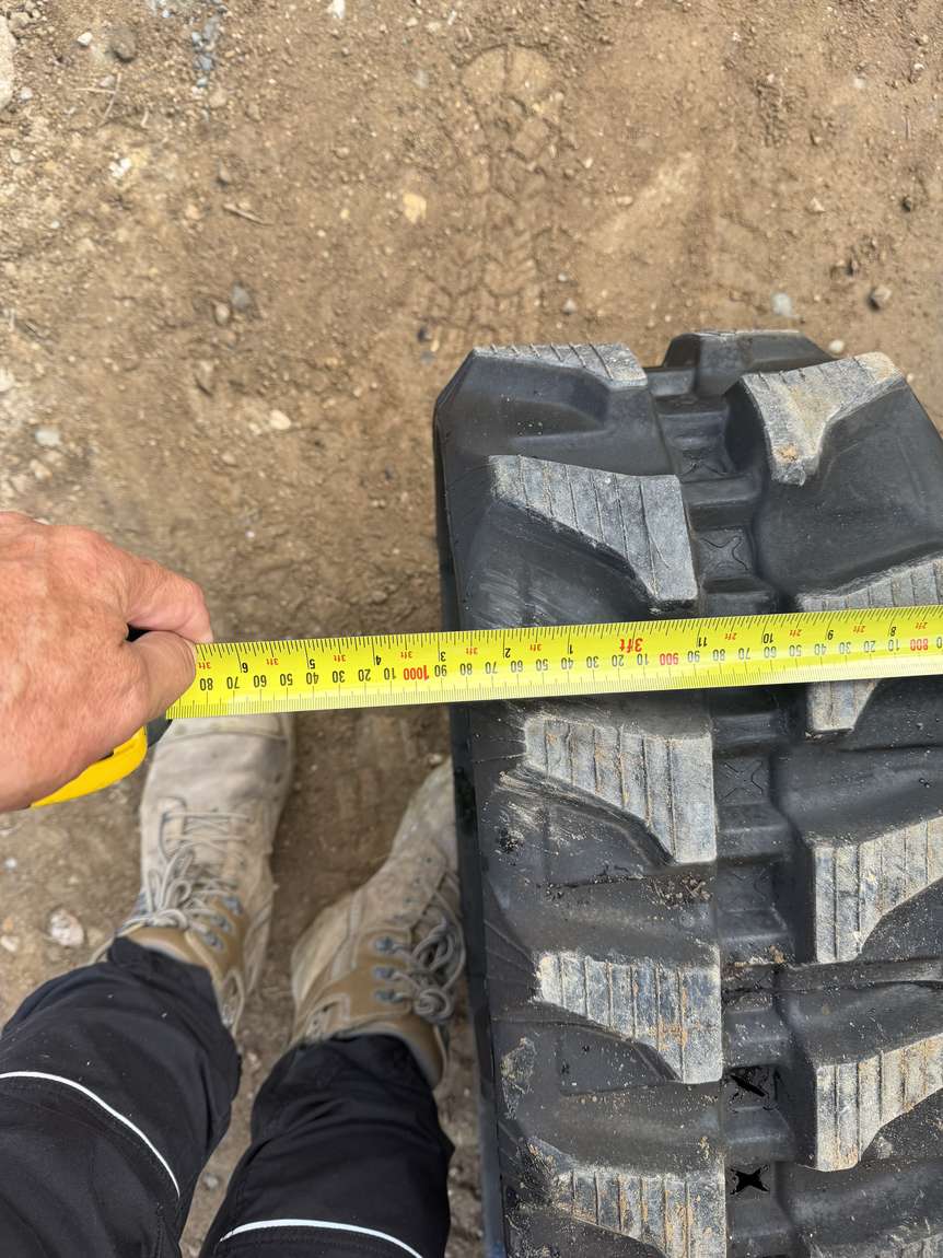 A tape measure held across the machine's rubber track
