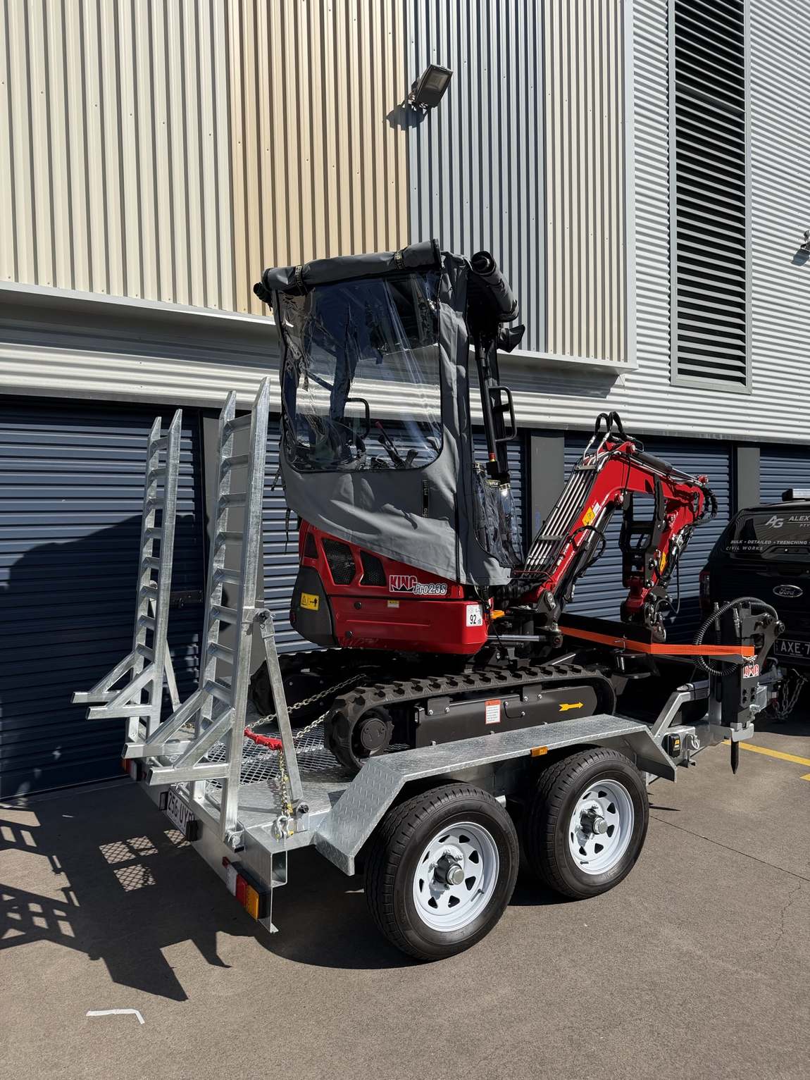 The excavator loaded and strapped on its trailer